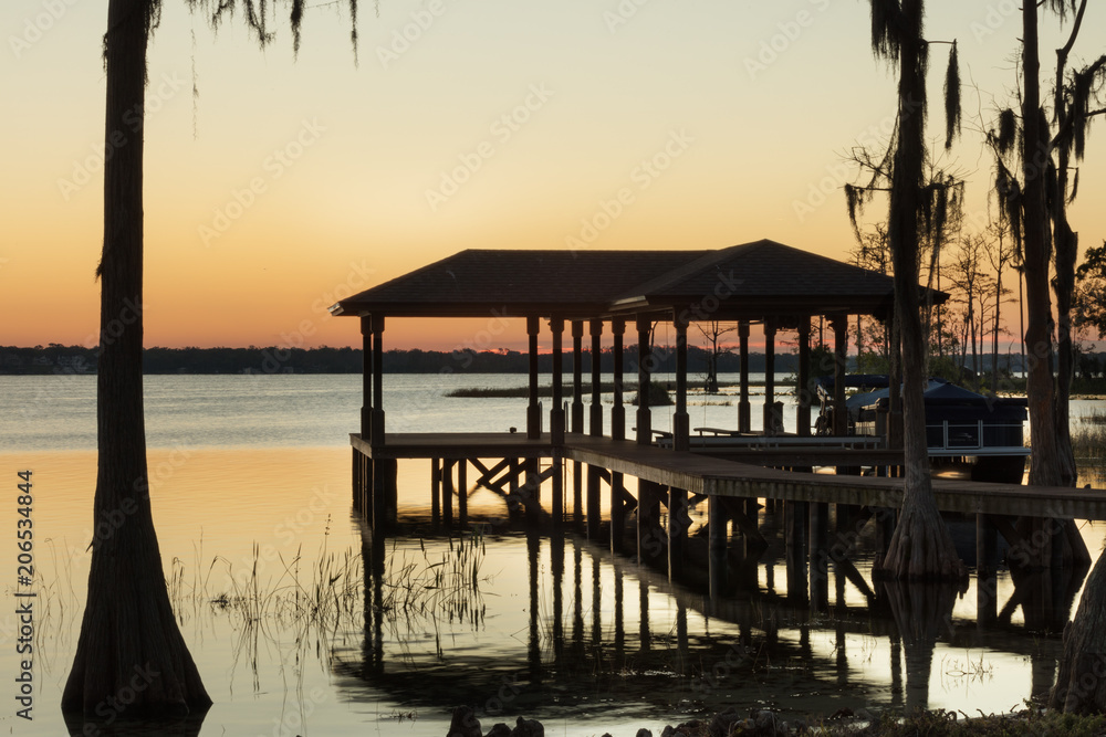 Lakefront Dock and Cypress Trees Silhouetted at Sunset