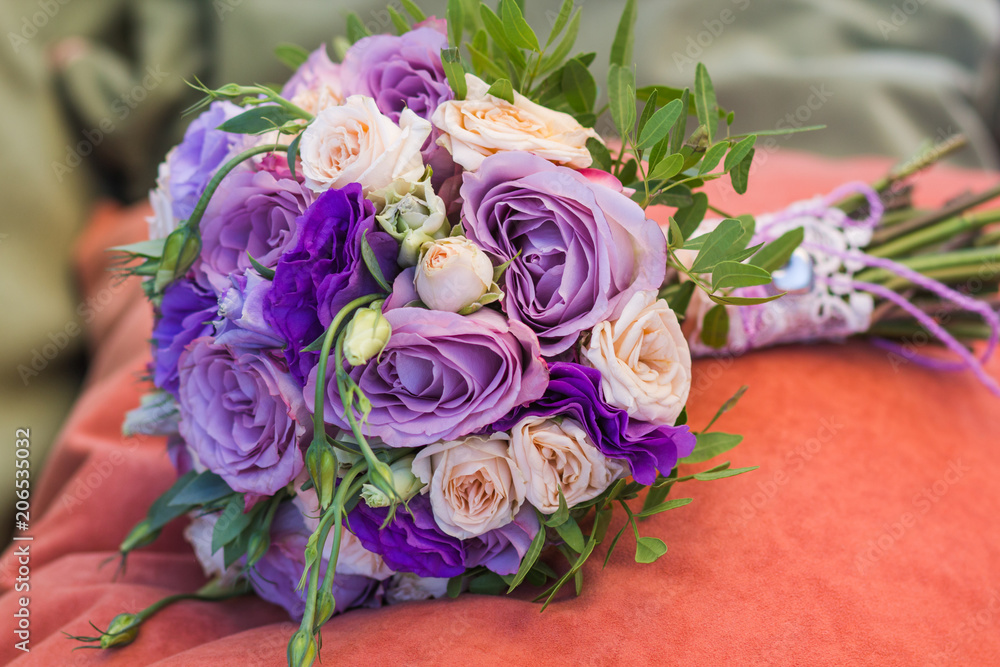 Fototapeta premium wedding bouquet on an orange pillow, bouquet of bride from rose cream spray, rose bush, rose purple Memory Lane, violet eustoma, eucalyptus