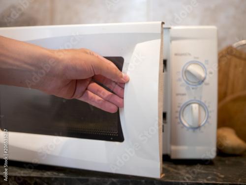 close up person's hand opens microwave oven to heat some fried food