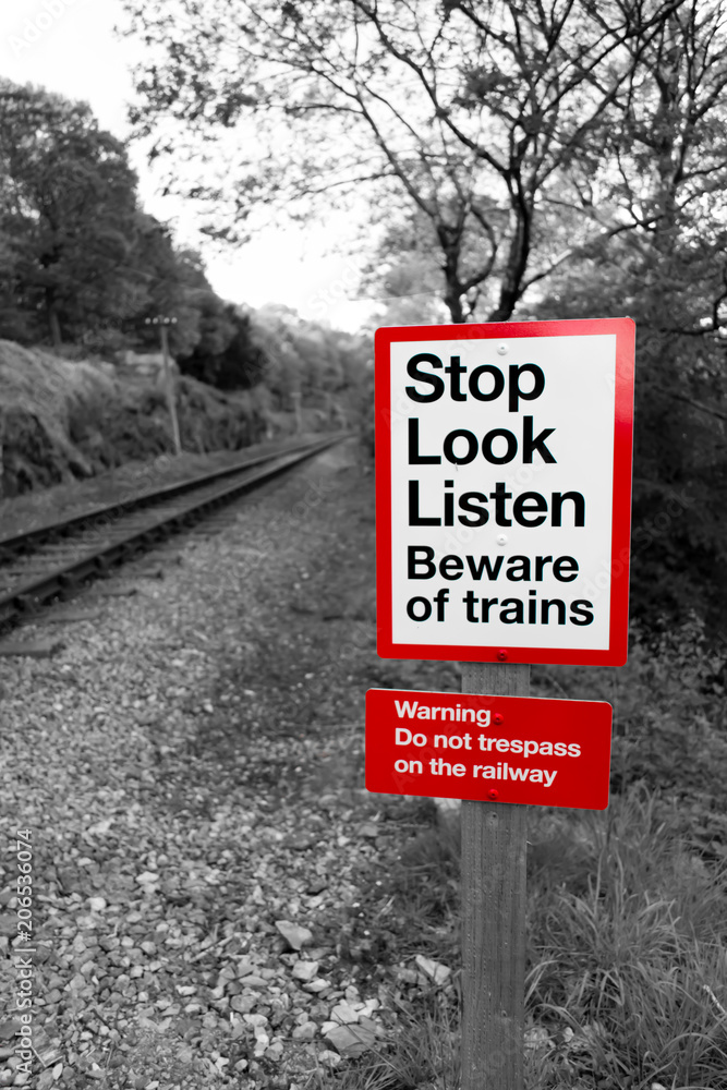 Railway warning sign in black and white with red signpost reading Railway warning sign in black and white with red signpost reading