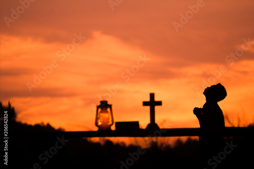 Boy praying with light sunset background.