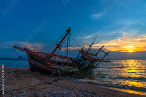 Wreck fishing boat with beautiful sunset on the beach.