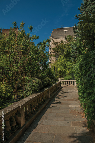 Sidewalk in wooded gardens of condos under sunny blue sky at Montmartre in Paris. Known as the “City of Light”, is one of the most impressive world’s cultural center. Northern France.