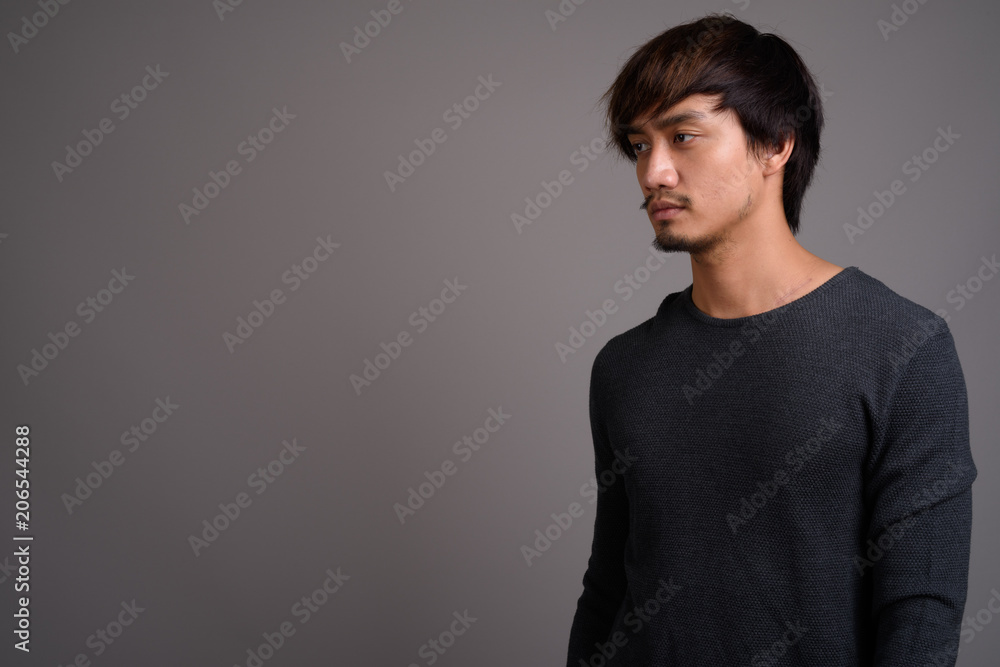 Fototapeta premium Young Asian man against gray background