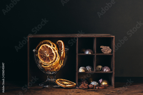 bowl with dry orange slices, nuts, chocolate candies and pieces on shelves