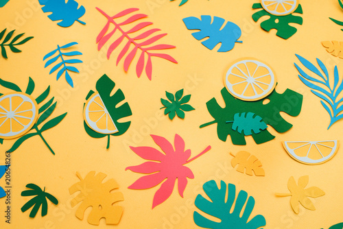 Tropical leaves and fruits pattern on a bright yellow background. Sunny summer colorful flat lay with paper cut outs.