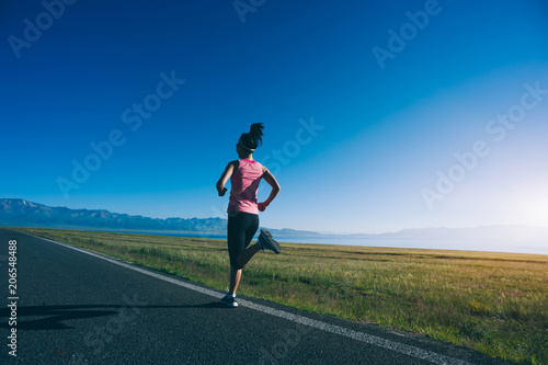 Young fitness sporty woman running on country road