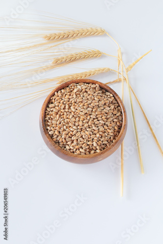 Wheat. Grains in a  wooden cup and ears of wheat on a light background. Vegan food. Healthy Eating