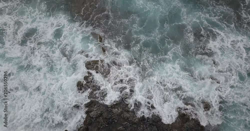 Aerial view of waves crashing on rocks. View is straight down. Aerial view of waves crashing on rocks. View is straight down.