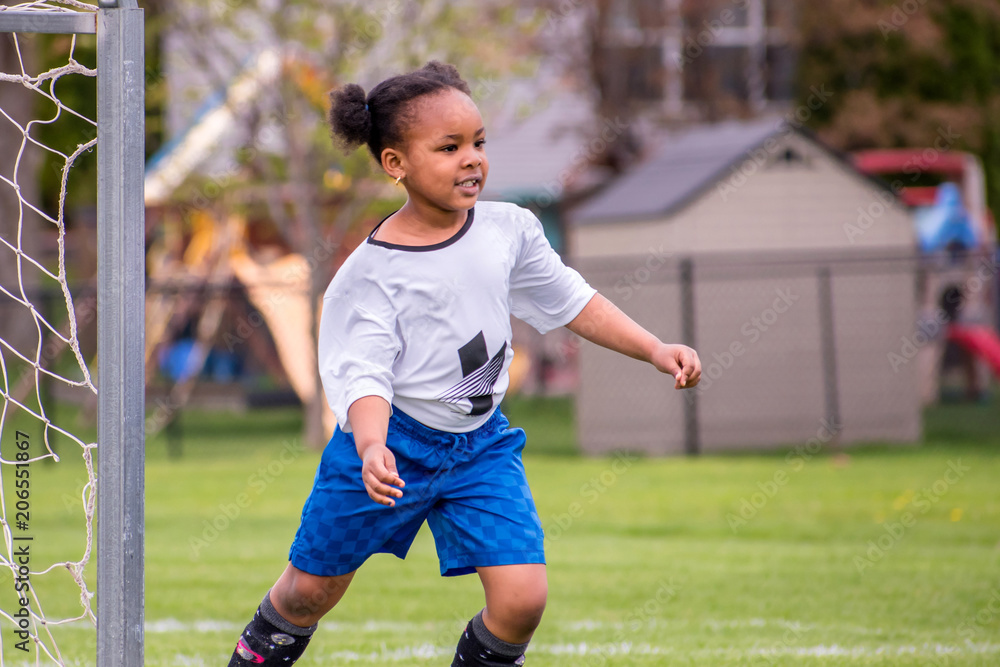 A young girl is learning how to play soccer	