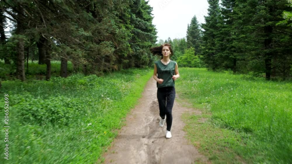 Sporty young woman does morning running in summer park Sporty young woman does morning running in summer park