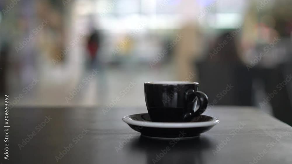 Hand putting a black cup on the table Hand putting a black cup on the table