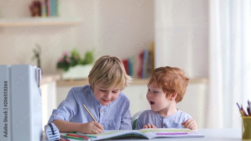 cute brothers drawing wiyh colored pencils at the desk at home cute brothers drawing wiyh colored pencils at the desk at home