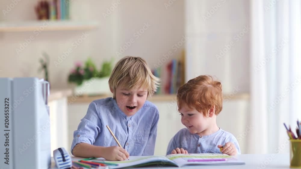 cute brothers drawing wiyh colored pencils at the desk at home cute brothers drawing wiyh colored pencils at the desk at home