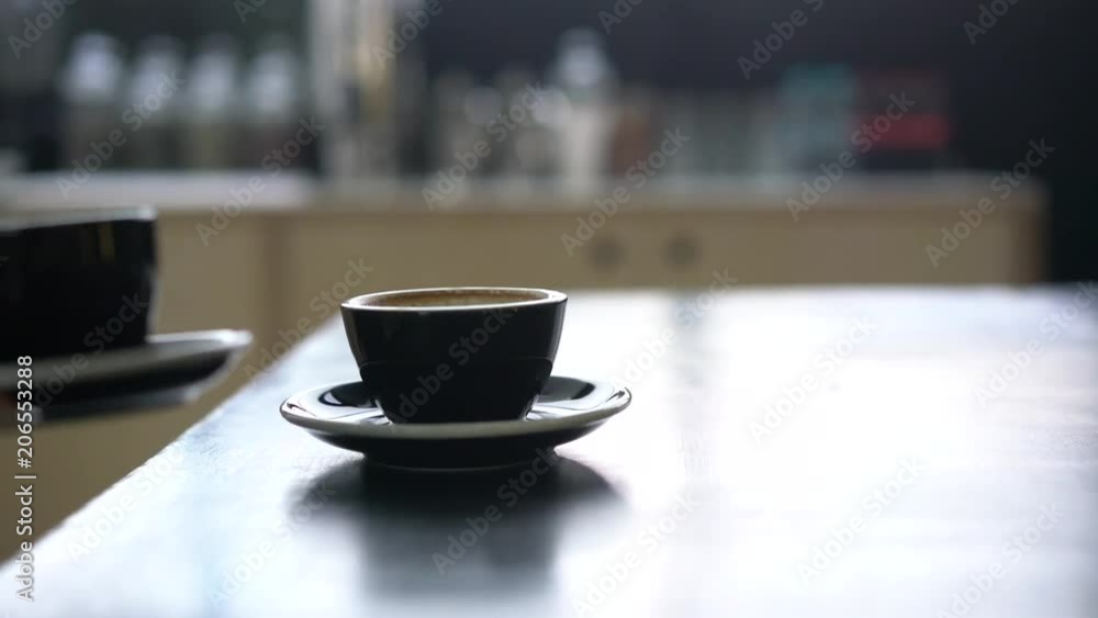 Hand putting a black cup on the table Hand putting a black cup on the table