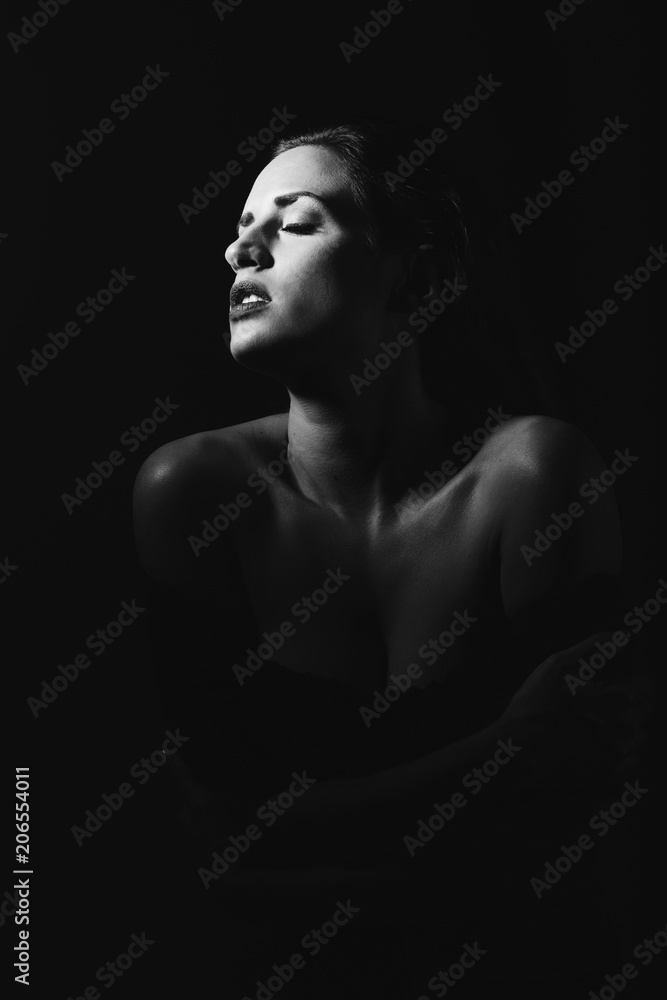Young brunette woman in black lingerie in chiaroscuro lighting
