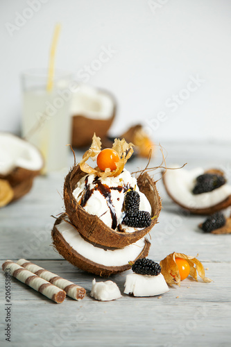 creative presentation of ice cream in coconut shell, decorated with mulberry and physalis berries