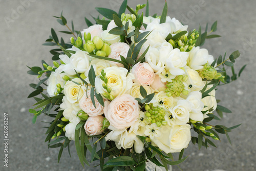 White Wedding Bouquet Roses Pink flowers and Ruscus Leaves with Robbons on Gray Asphalt Background. Wedding Decoration