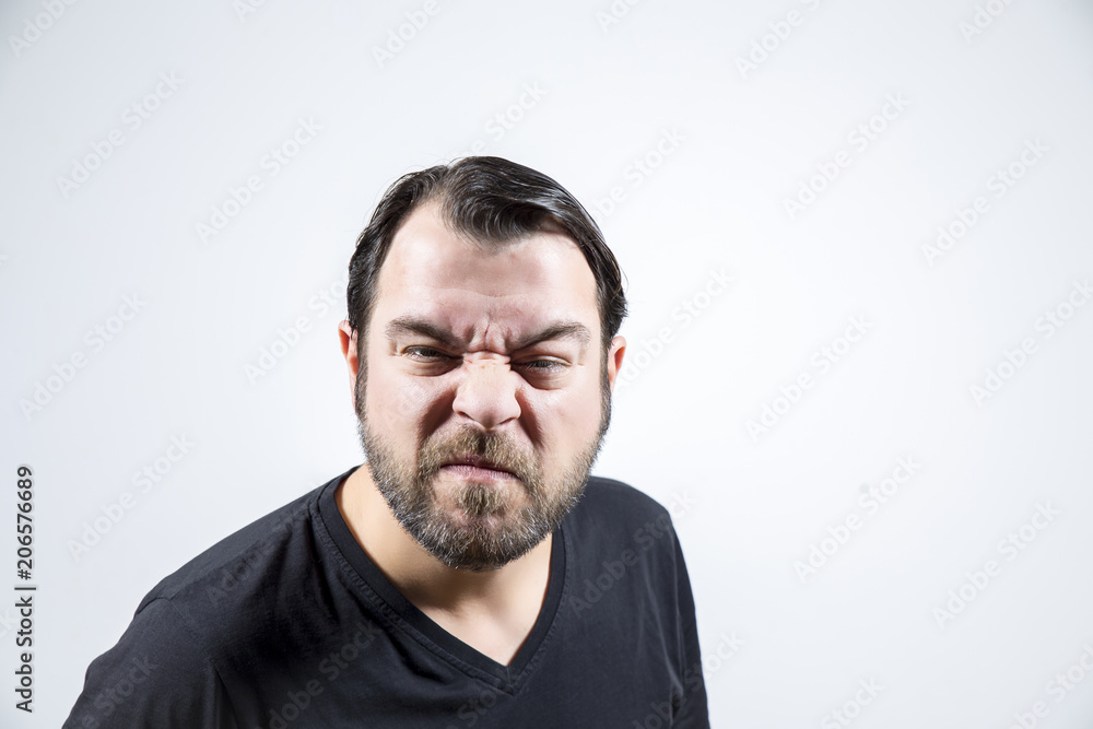 Adult man with frowning face is looking to the camera Adult man with frowning face is looking to the camera