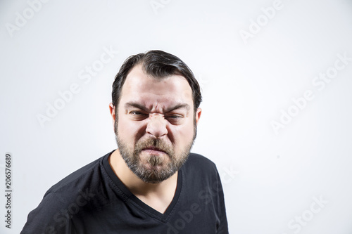Adult man with frowning face is looking to the camera