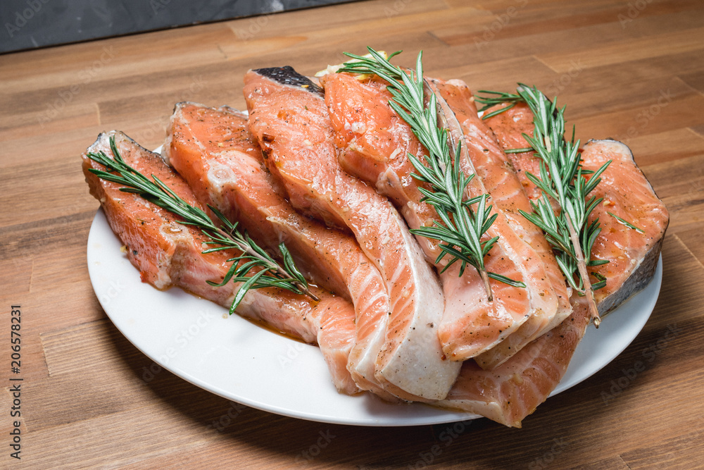 Raw salmon fillet with rosemary pepper thymus and salt on wooden cutting board Raw salmon fillet with rosemary pepper thymus and salt on wooden cutting board