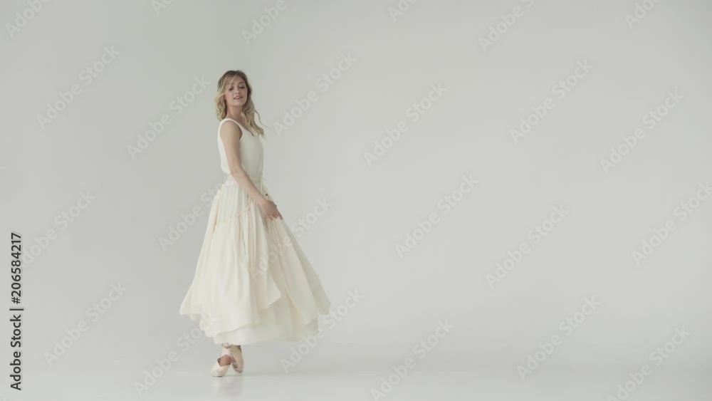ballerina in a light studio dances in pointe shoes. ballet dancer in a light fluttering long dress
