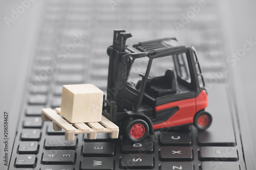 Forklift miniature with wooden block on laptop keyboard