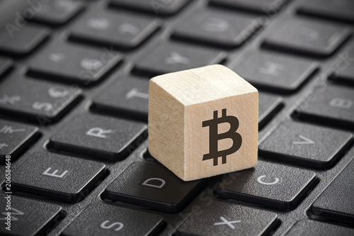Wooden block with bitcoin graphic on laptop keyboard