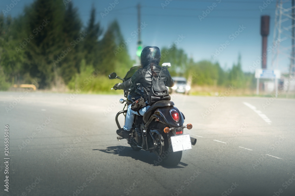 Sexy biker female in black leather jacket and helmet sit on vintage big black motorcycle. Traveling and active hipster lifestyle. Girls power.