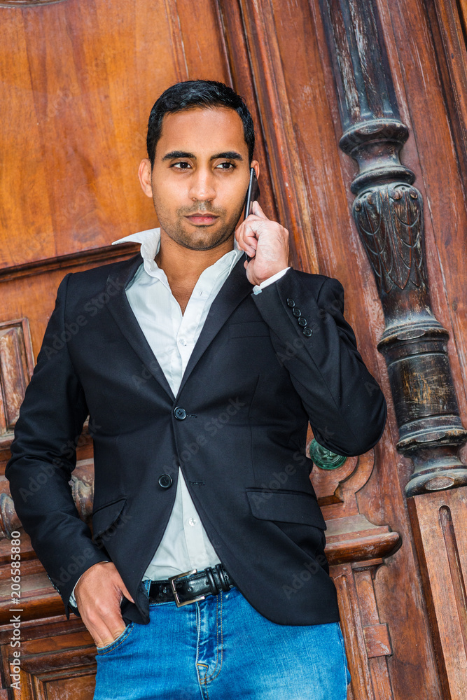 Young Handsome Hispanic American Businessman working in New York, wearing  black blazer, white shirt, blue jeans, standing against old office door,  calling on cell phone.. Stock Photo | Adobe Stock