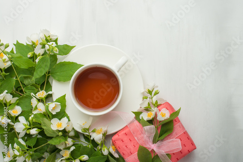 Flowers and gifts and a cup of tea on a light background. It is possible to use both for inscription, demonstration of fonts, and as a postcard