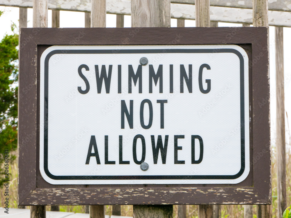 An american warning sign at the beach with man swim and not symbol, Caution No Swimming allowed