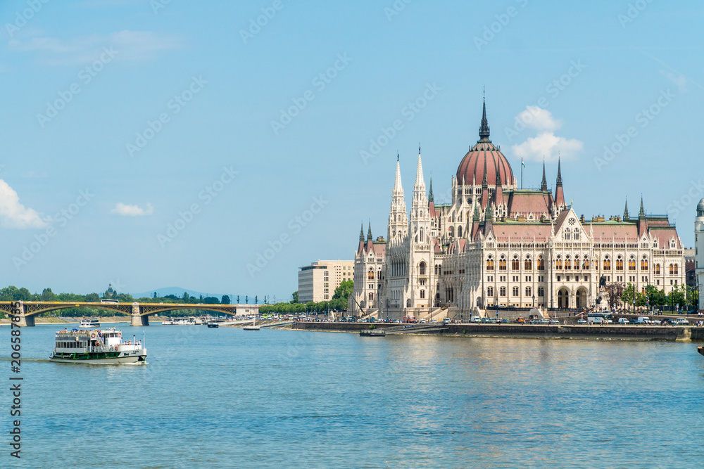 Hungarian Parliament and travel boats sailing the Danube river in Budapest, Hungary.