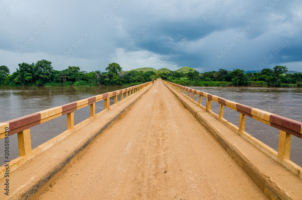 Simple dirt road bridge over tropical river with dramatic clouds in Republic of Congo, Africa Simple dirt road bridge over tropical river with dramatic clouds in Republic of Congo, Africa