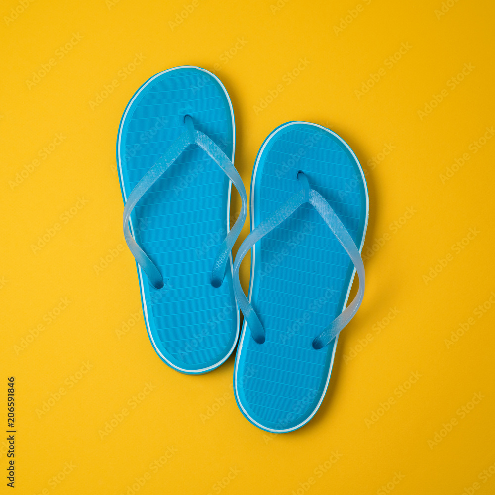 Blue flip flops over yellow background Blue flip flops over yellow background