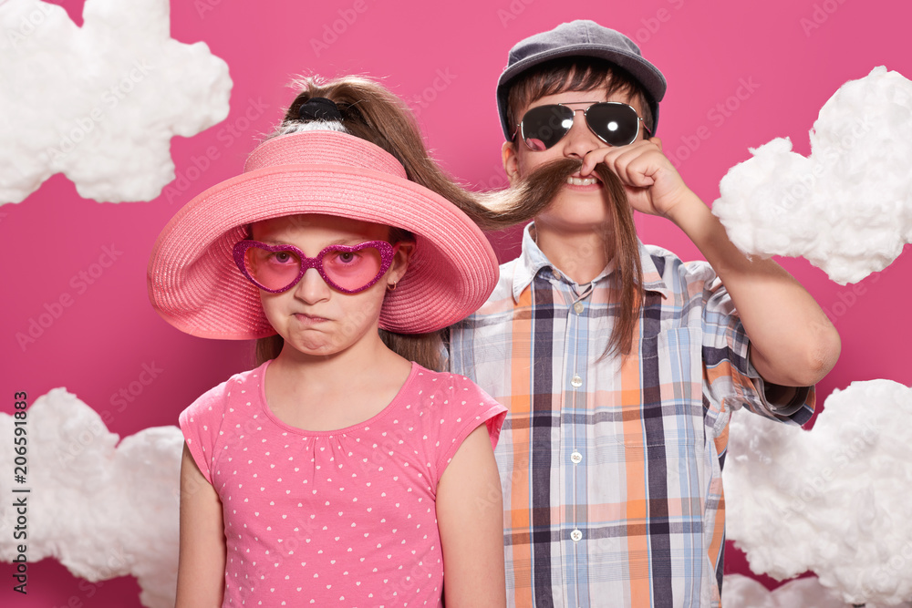 fashionable girl and boy posing on a pink background with clouds fashionable girl and boy posing on a pink background with clouds