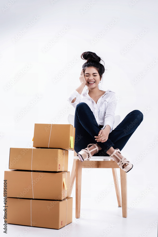 The lady in white shirt and blue jean is posing by sitting on wooden chair with smile and happy face and put her hand ,shopping post box put on ground floor The lady in white shirt and blue jean is posing by sitting on wooden chair with smile and happy face and put her hand ,shopping post box put on ground floor