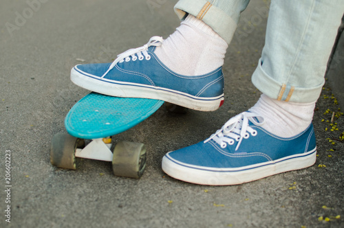 Blue skate shoe on the skateboard. The concept of modern culture, penny skateboarding, outdoor activity, modern lifestyle.