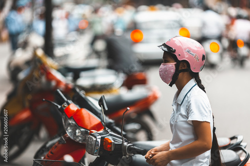 HANOI, VIETNAM. JUNE 28, 2009: Woman waiting on her motorbike in the street of Hanoi, Vietnam