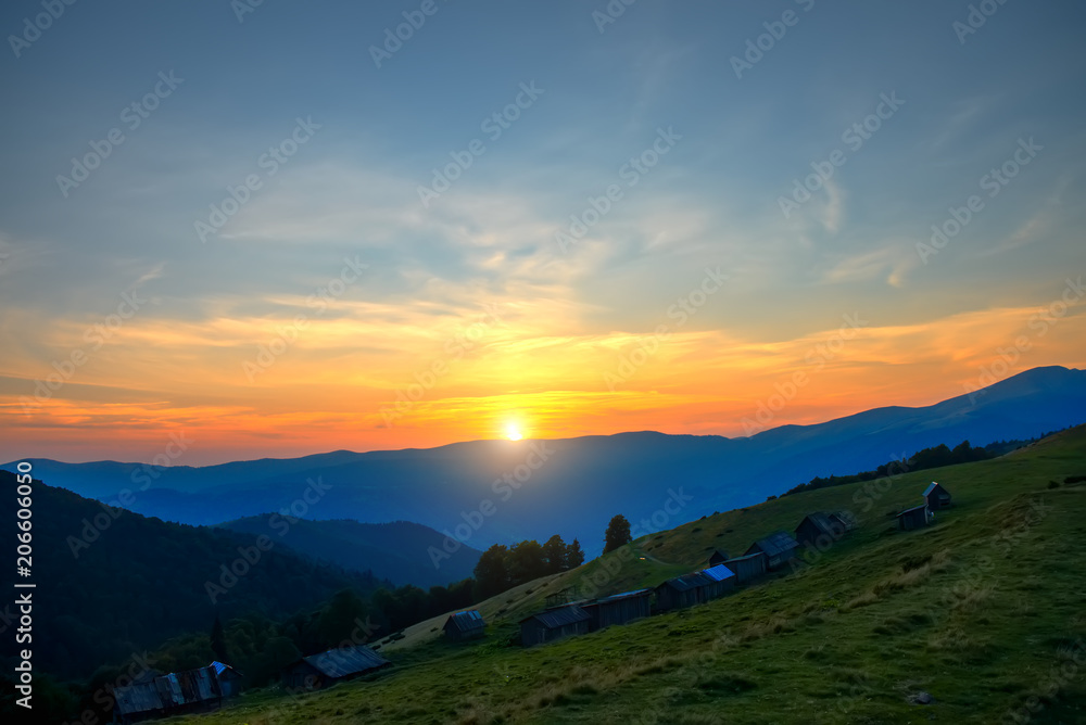 Sunset in the mountains, wooden houses on the mountainside, nature background