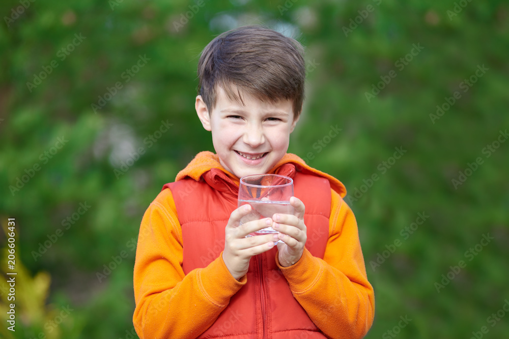 Outdoor portrait of happy Caucasian boy with a glass of water. Outdoor portrait of happy Caucasian boy with a glass of water.