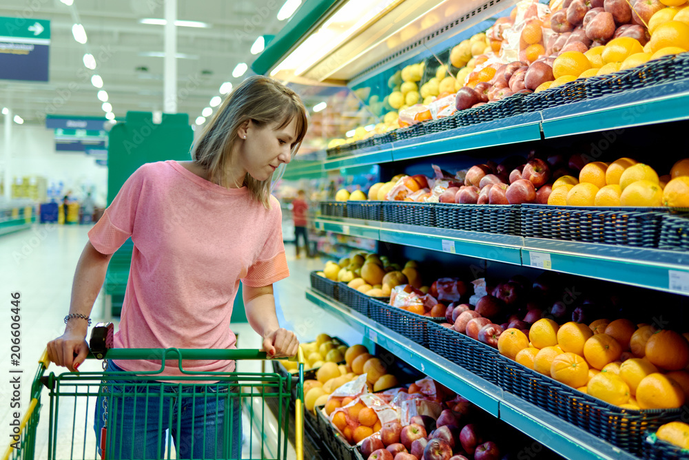 Caucasian Woman choosing apples during shopping at supermarket.