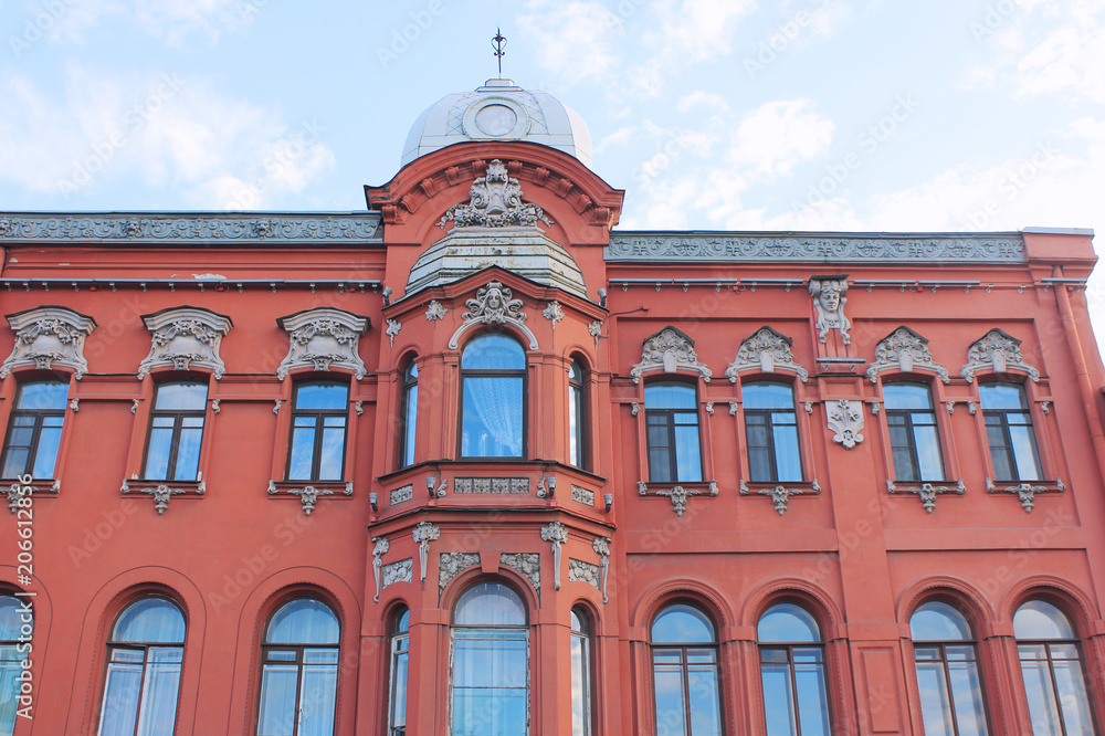 Classic Architecture Building Ornamental Facade of Old Historical House with Sculptures and Red Colored Walls. Exterior Design of Apartment Building Front View. Minimalist Style European Architecture.