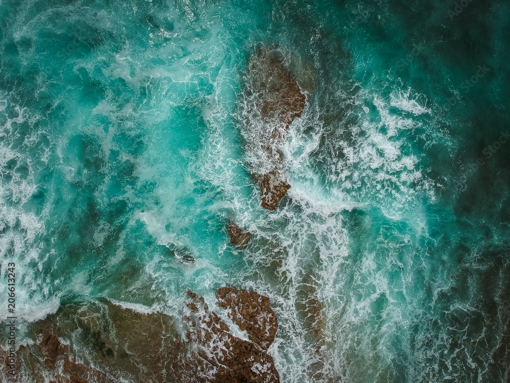 Aerial view of ocean waves and brown rocks in the coastline Aerial view of ocean waves and brown rocks in the coastline