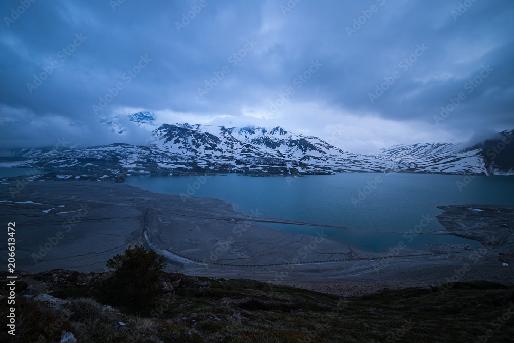 clouds at dusk blue hour, lake and snowcapped mountain, cold winter, fjord nord landscape