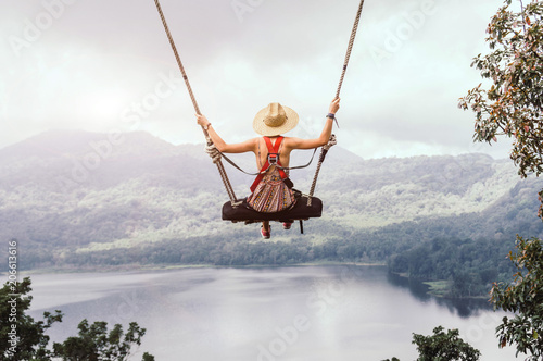 Carefree woman on the swing on a inspiring landscape.