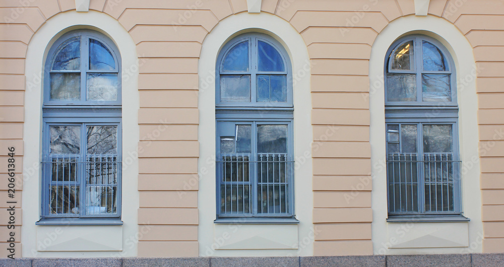 Three Arch Windows in Row on Building Wall of Classic Stone House. Architecture Detail of Historic Pale Yellow and White Colored Building Facade Exterior with Arched Windows Close Up View.