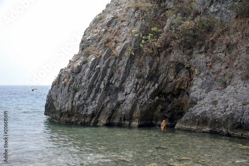 Persons taking a bath at a beach with a cliff