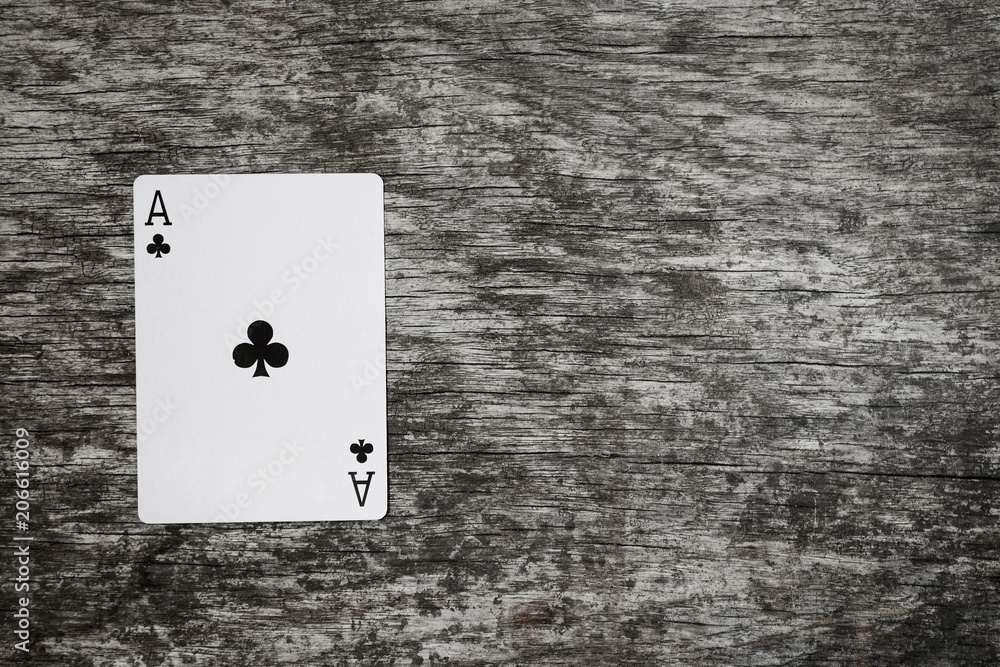 ace of clubs playing card on wooden table