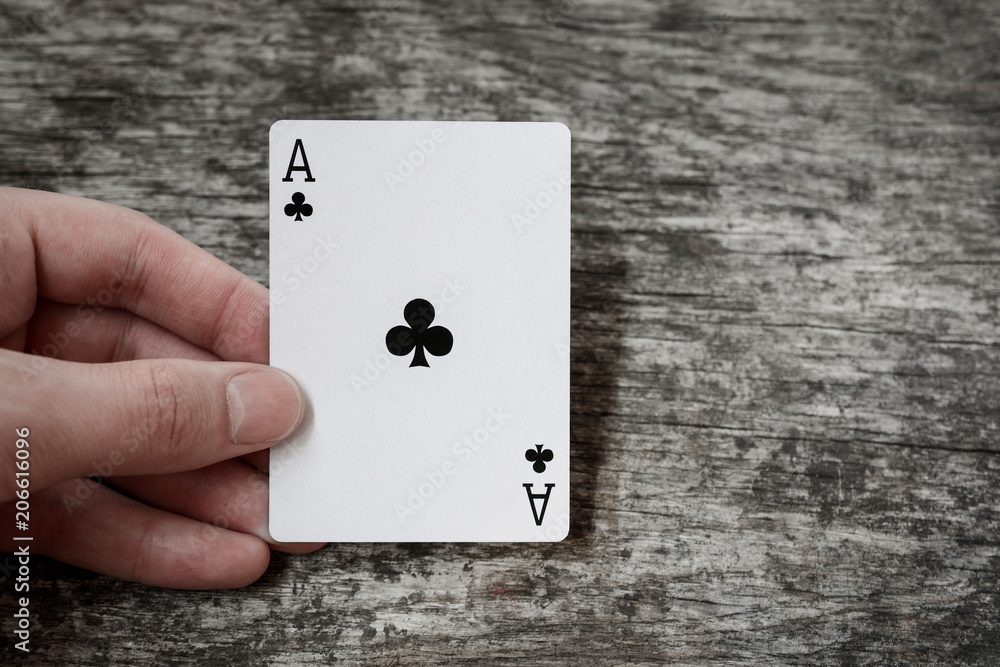 man holding playing card ace of clubs